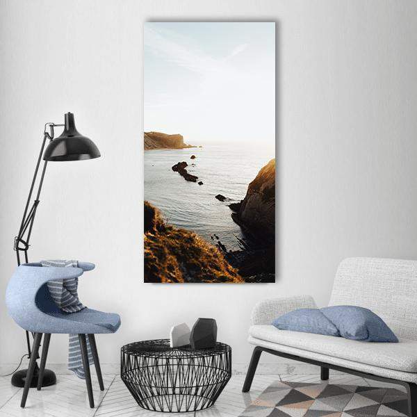 Coastal Cliffs at Sunlit Beach Vertical Canvas Wall Art in white, brown and blue, single vertical panel hung on a wall