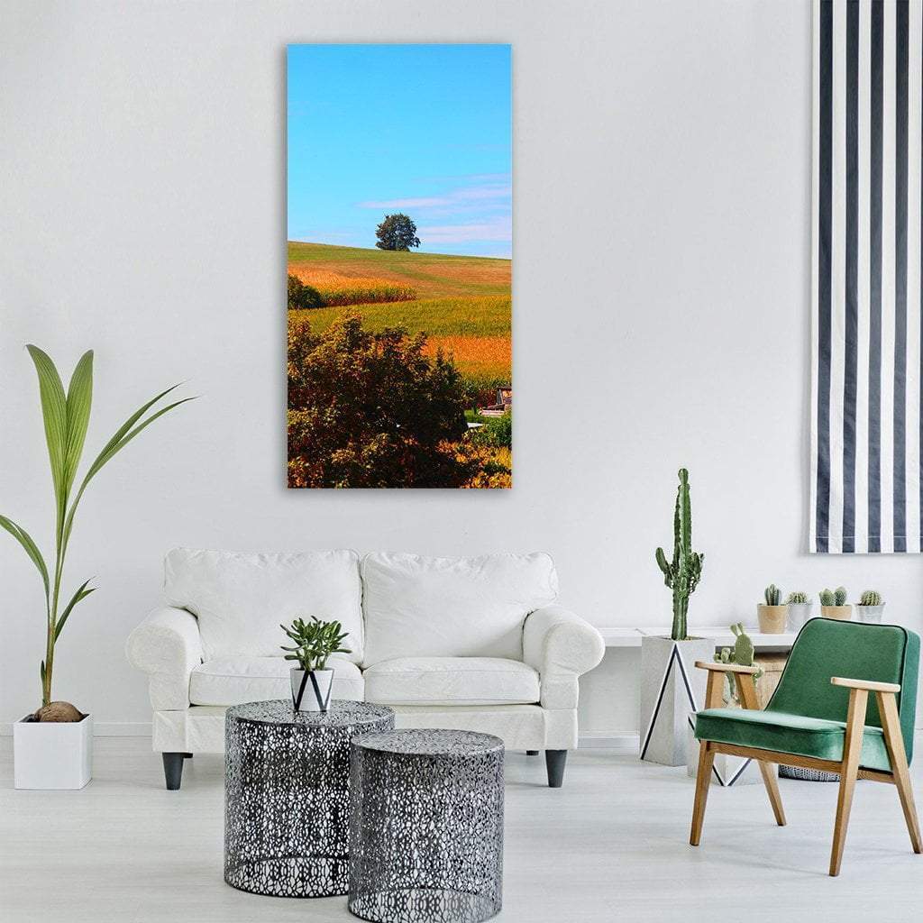 Lone Tree Over Autumn Fields Vertical Canvas Wall Art in yellow, green and blue, single vertical panel hung on a wall