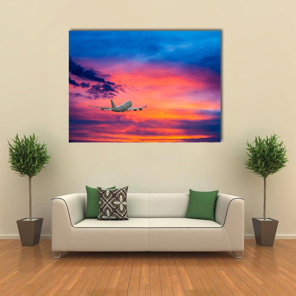 Passenger Jet Over Vibrant Sunset Clouds Canvas Wall Art in orange, blue and pink, single panel hung on a wall
