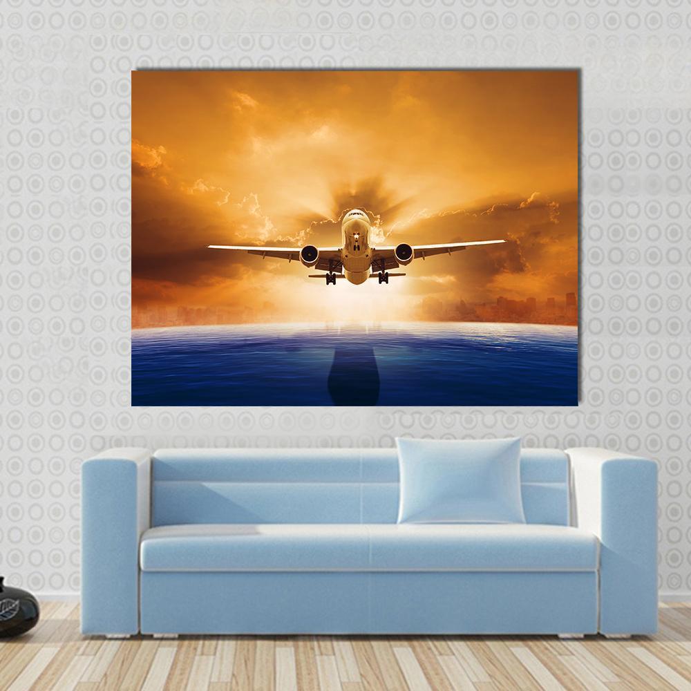 Airplane Flying Above Ocean Canvas Wall Art in orange, yellow and blue, single panel hung on a wall
