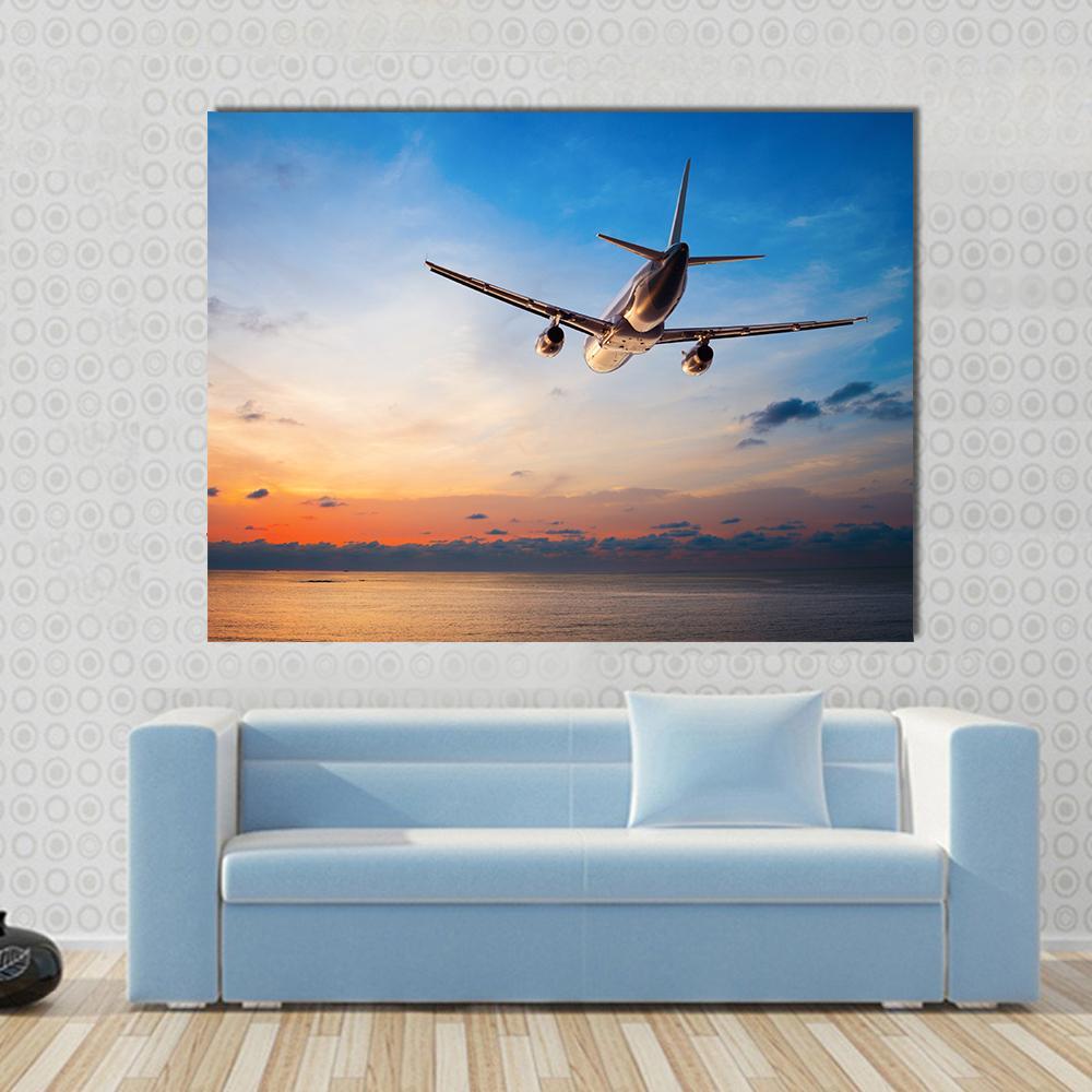 Airplane Flying Above Tropical Sea Canvas Wall Art in orange, yellow and blue, single panel hung on a wall