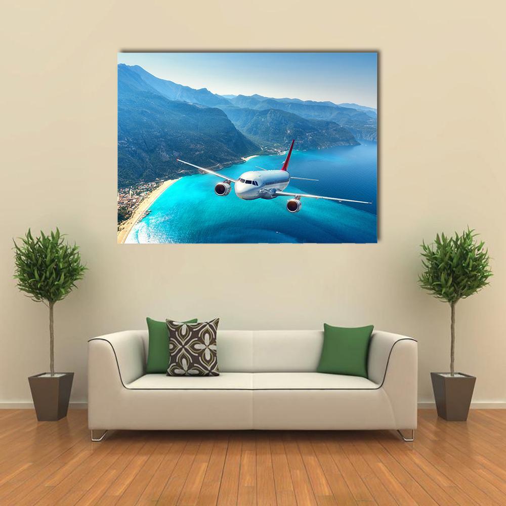 Commercial Airplane Over Ocean Coastline Canvas Wall Art in white, green and blue, single panel hung on a wall