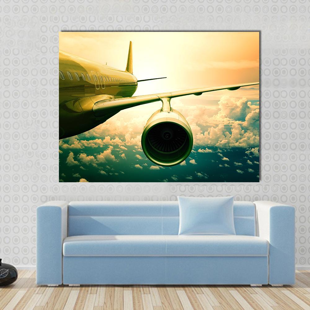 Airplane Wings Flying Above Clouds Canvas Wall Art in yellow, green and blue, single panel hung on a wall
