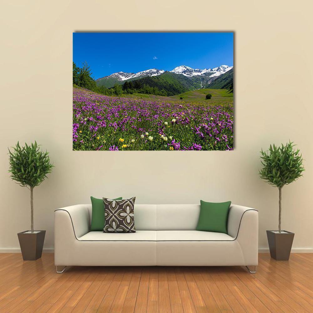 Alpine Fields with Purple Flowers Canvas Wall Art in green, blue and purple, single panel hung on a wall