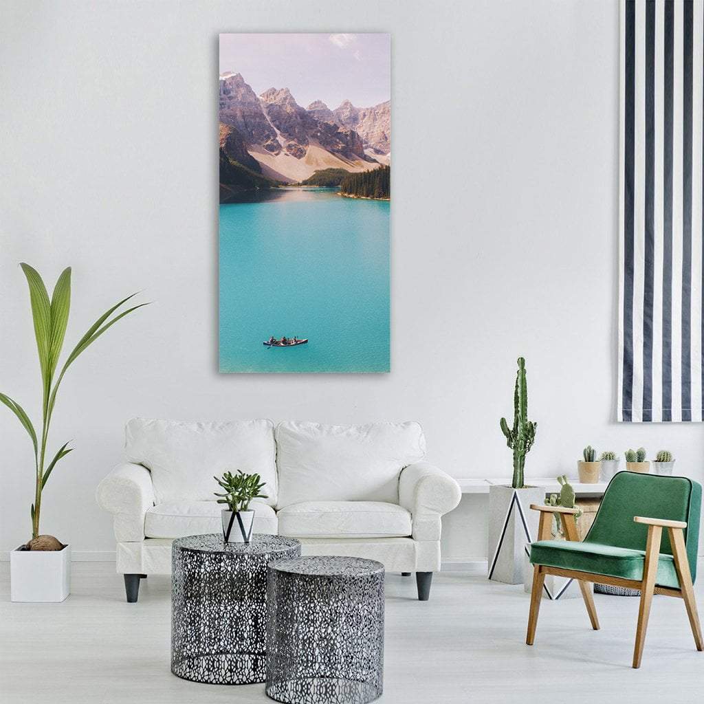 Canoe on Turquoise Lake with Snow-capped Mountains Vertical Canvas Wall Art in gray, brown and blue, single vertical panel hung on a wall