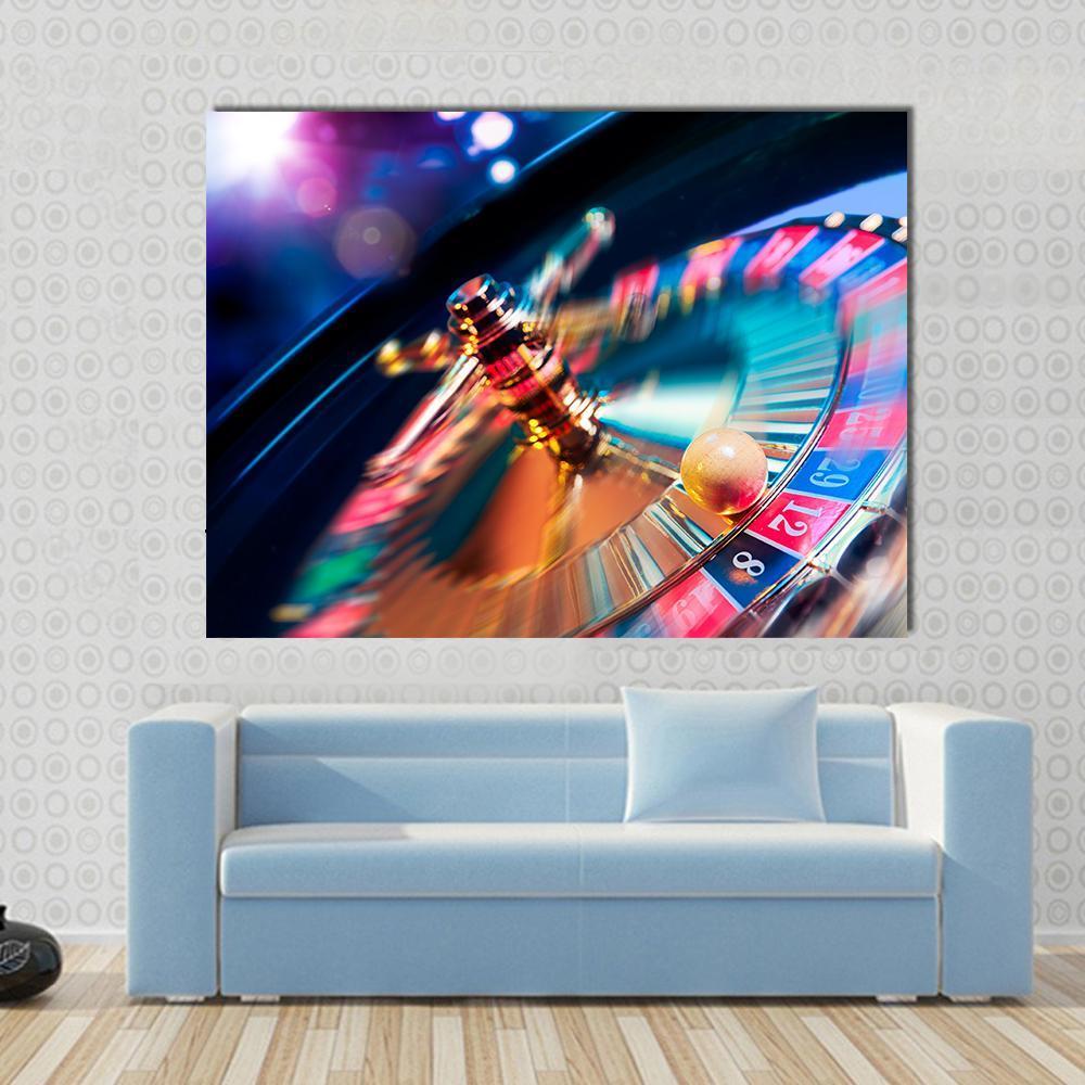 Casino Wheel in Motion Canvas Wall Art in gold, red and blue, single panel hung on a wall