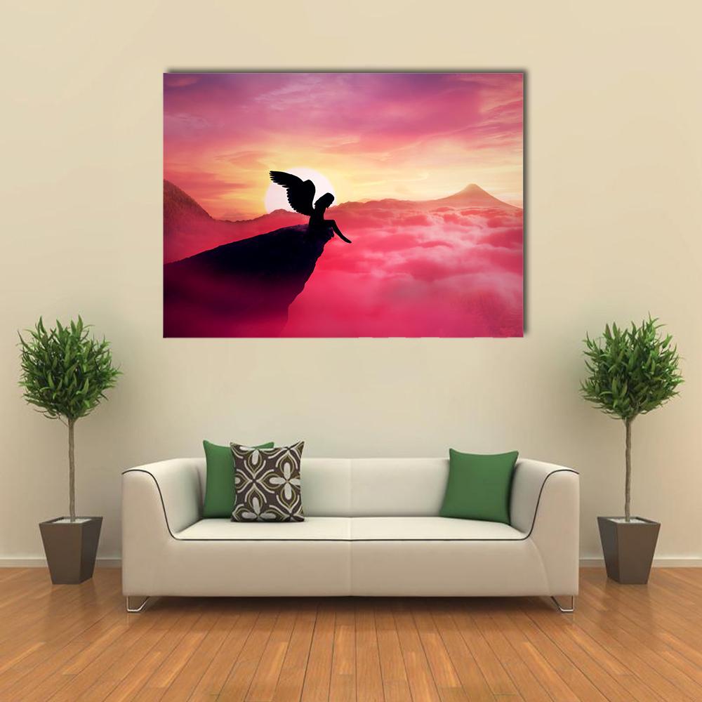 Winged Silhouette on Cliff at Sunrise Panoramic Canvas Wall Art in orange, purple and pink, single panel hung on a wall