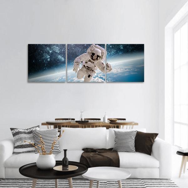 Astronaut Above Earth's Curvature Panoramic Canvas Wall Art in black, white and blue, hung on a wall