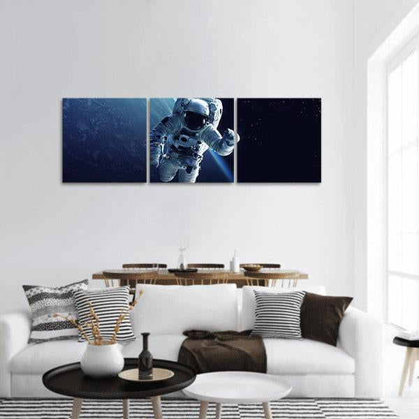 Astronaut Above Earth's Curve Panoramic Canvas Wall Art in black, white and blue, hung on a wall