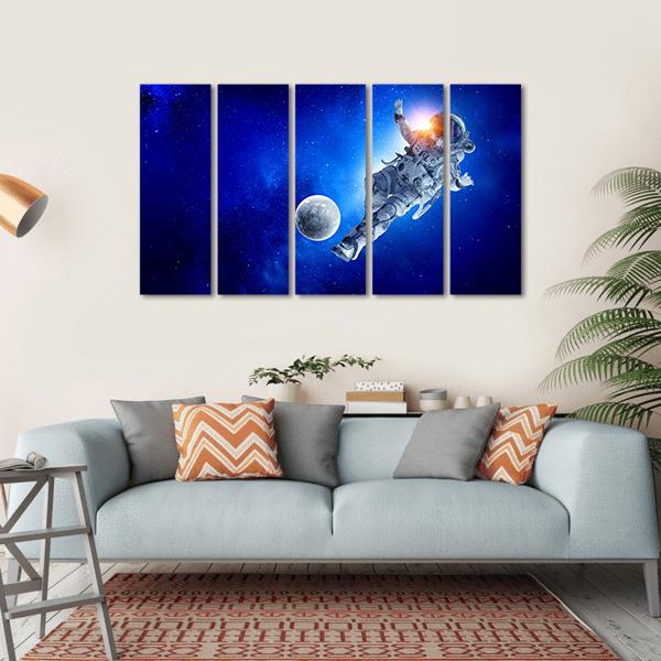 Astronaut Playing Soccer in Space Canvas Wall Art in black, white and blue, hung on a wall