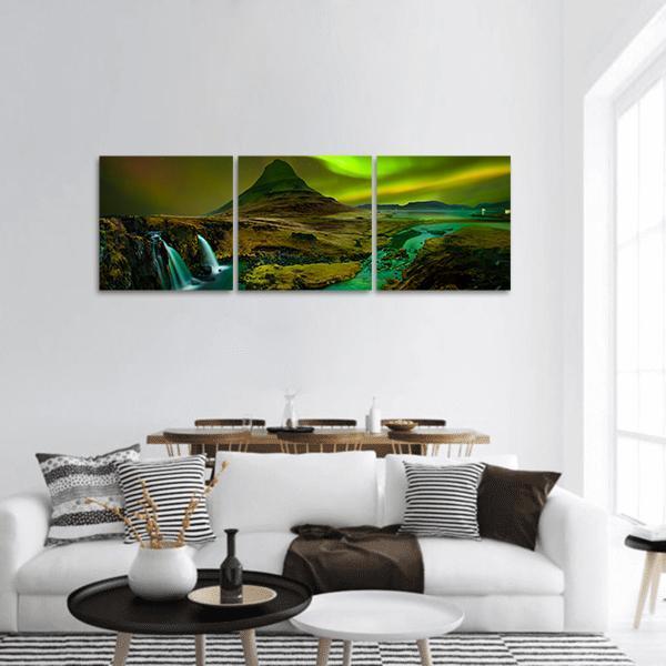 Northern Lights Above Cone-shaped Mountain and Waterfalls Panoramic Canvas Wall Art in black, yellow and green, hung on a wall