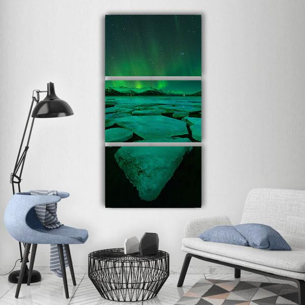 Northern Lights Over Ice Floes Vertical Canvas Wall Art in black, green and blue, single vertical panel hung on a wall