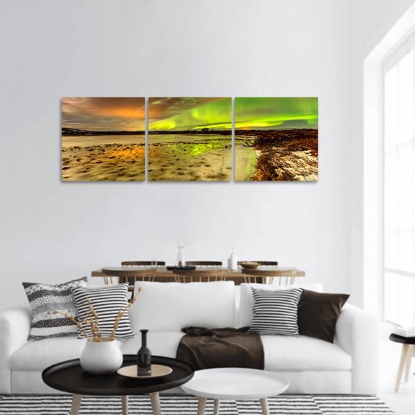 Aurora Borealis Over Frozen Lake Panoramic Canvas Wall Art in brown, yellow and green, hung on a wall