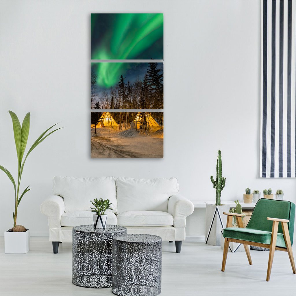 Aurora Village Under Northern Lights Vertical Canvas Wall Art in black, yellow and green, single vertical panel hung on a wall