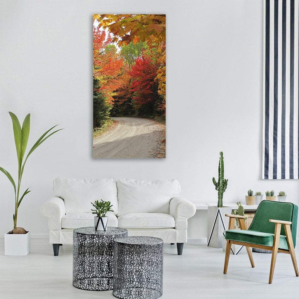 Winding Autumn Road Through Fall Forest Vertical Canvas Wall Art in red, orange and yellow, single vertical panel hung on a wall