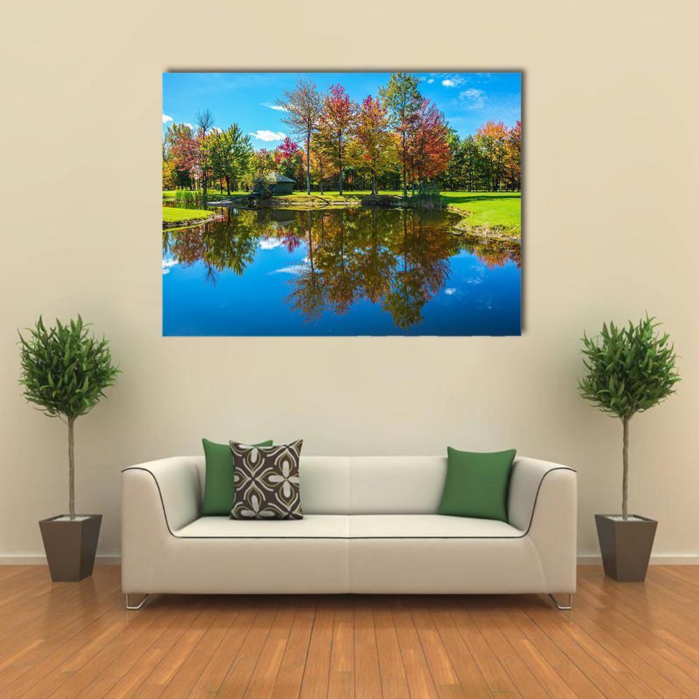 Autumn Foliage Reflection on Lake Canvas Wall Art in orange, green and blue, single panel hung on a wall