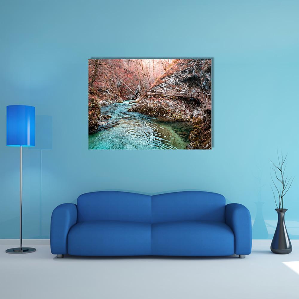 Autumn Footbridge by Forest River Canvas Wall Art in brown, orange and blue, single panel hung on a wall