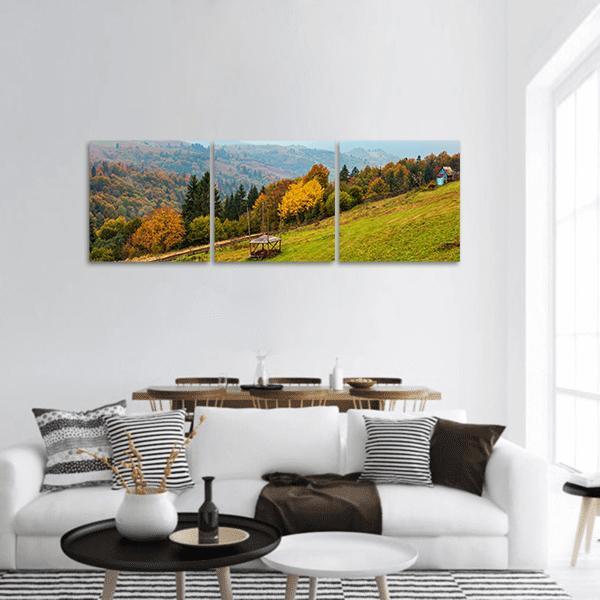 Carpathian Autumn Hills with Blue Cottage Panoramic Canvas Wall Art in brown, yellow and green, hung on a wall
