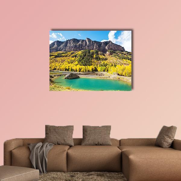 Autumn Lake with Rocky Shore Canvas Wall Art in yellow, green and blue, single panel hung on a wall