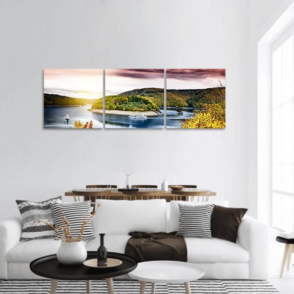 Autumn River Landscape at Sunset Panoramic Canvas Wall Art in orange, yellow and blue, hung on a wall