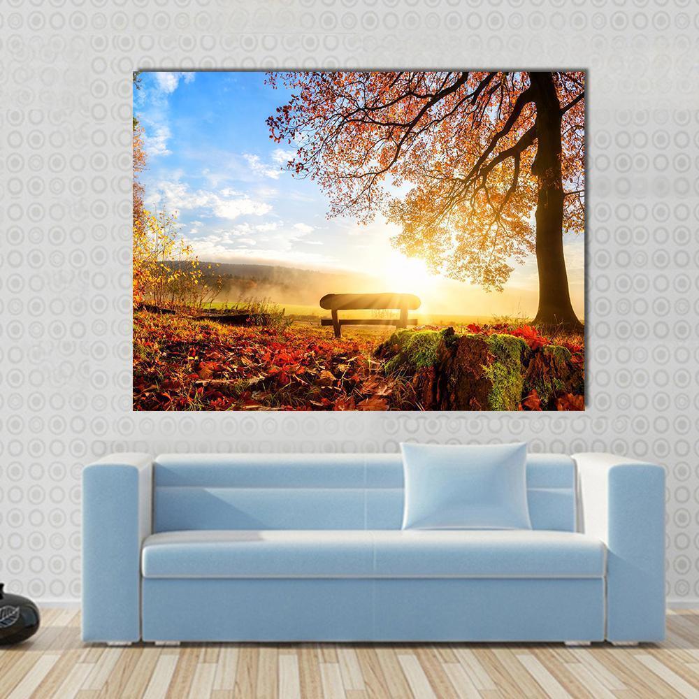 Autumn Sunrise Over Park Bench Canvas Wall Art in orange, yellow and blue, single panel hung on a wall
