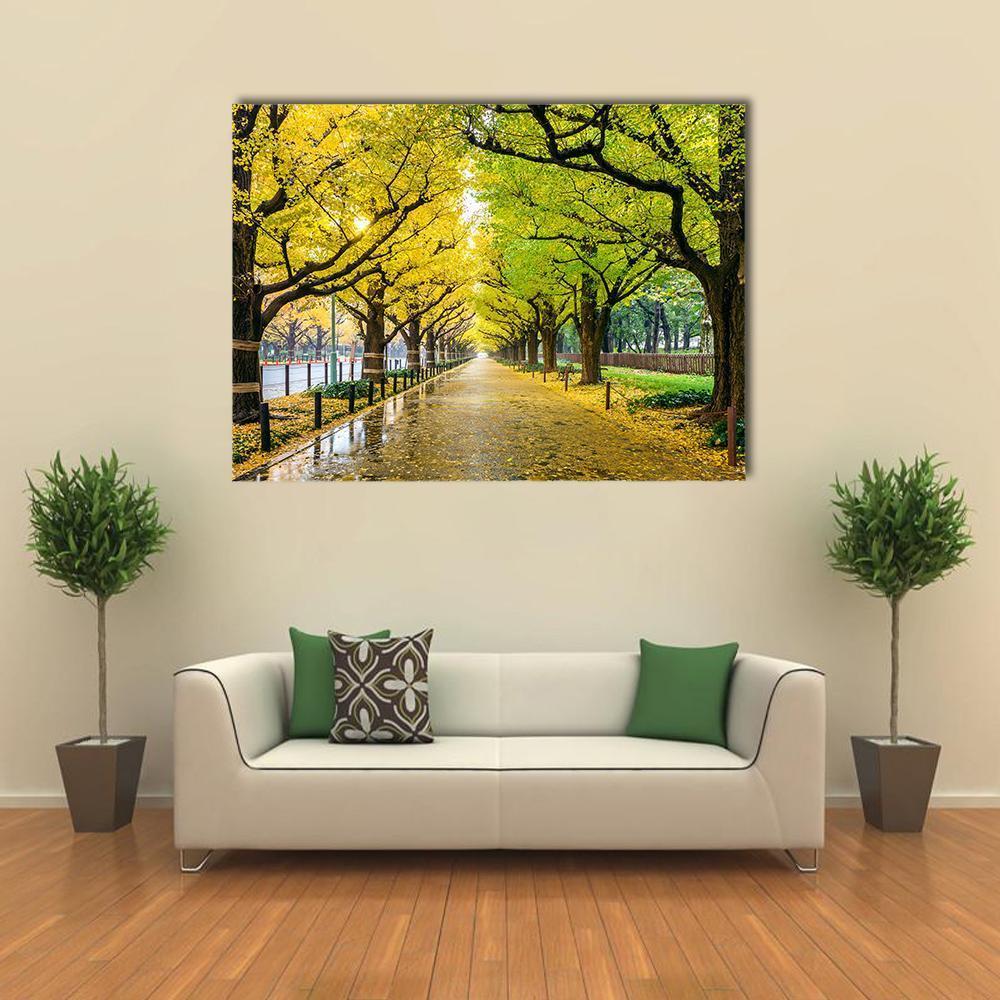 Autumn Avenue with Fallen Leaves Canvas Wall Art in brown, yellow and green, single panel hung on a wall