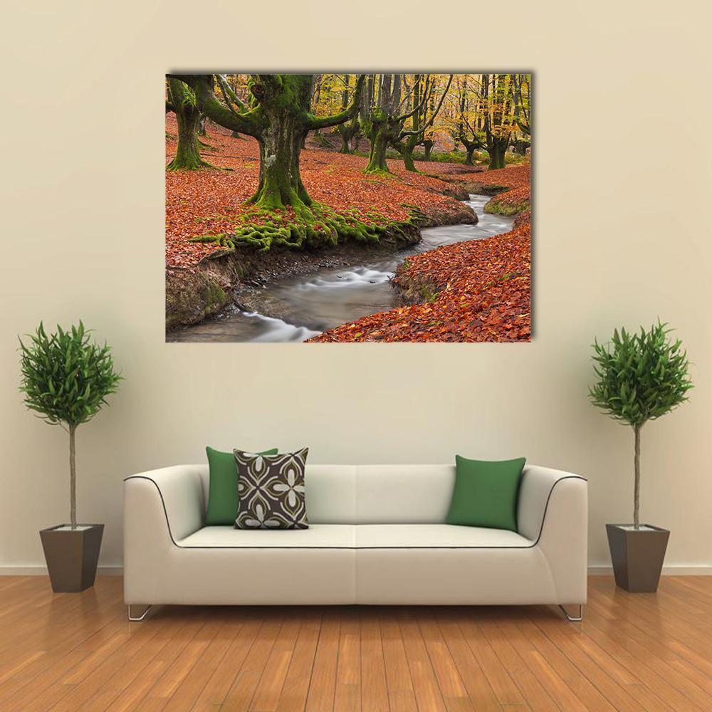 Autumn Forest Stream with Mossy Trees Canvas Wall Art in brown, orange and green, single panel hung on a wall