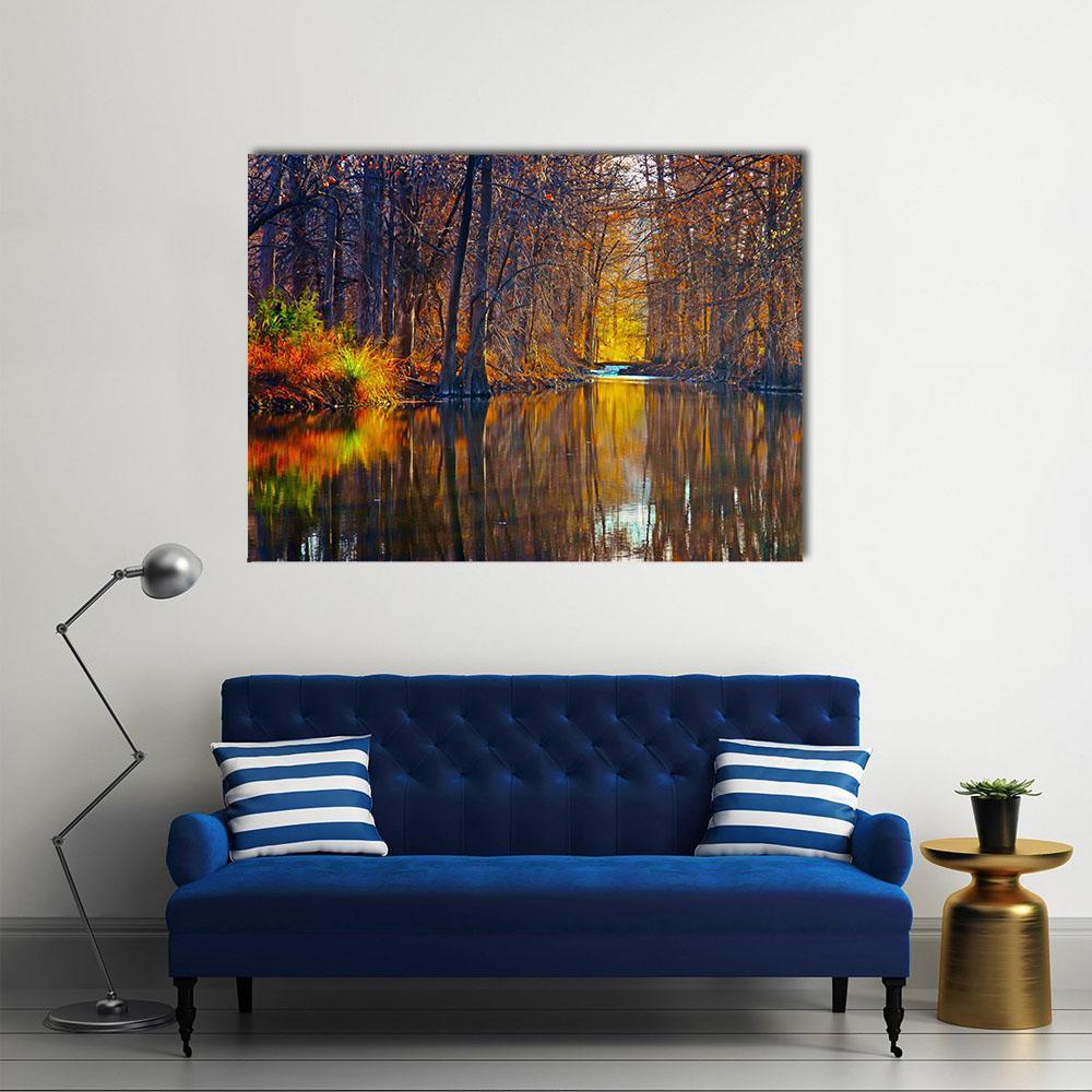 Autumn Trees Along River Canvas Wall Art in brown, orange and yellow, single panel hung on a wall