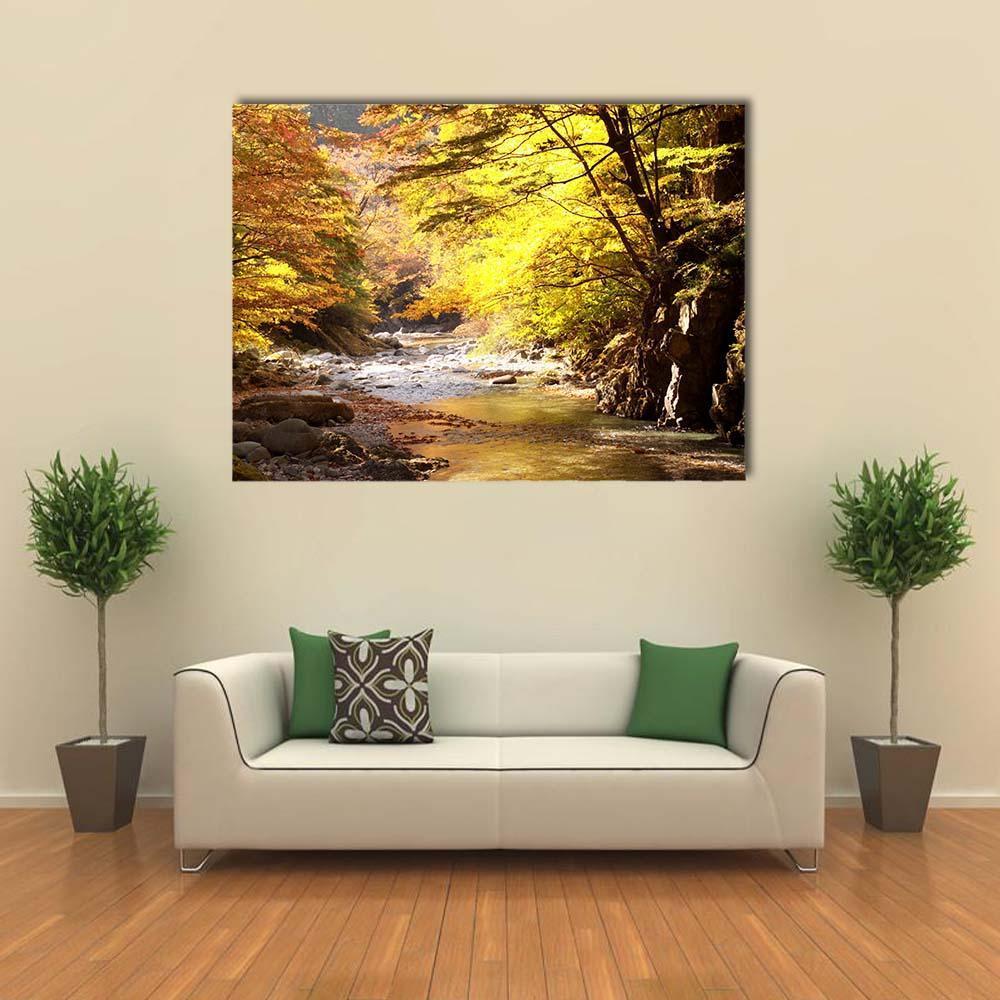Sunlit Autumn Stream in Forest Canvas Wall Art in brown, orange and yellow, single panel hung on a wall
