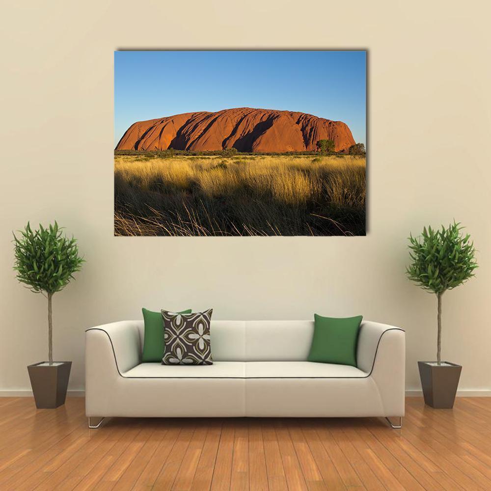 Ayers Rock in the Evening Canvas Wall Art in brown, yellow and blue, single panel hung on a wall