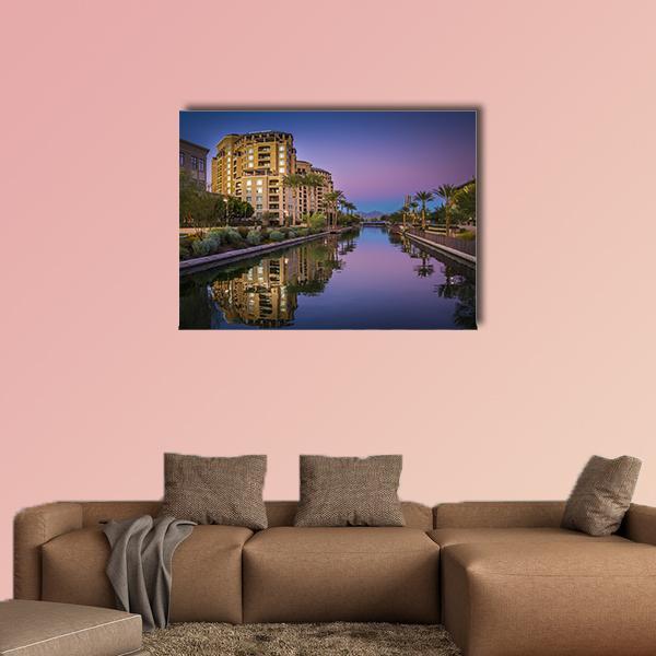 Dusk Canal Reflection with Palm Trees Canvas Wall Art in beige, blue and purple, single panel hung on a wall