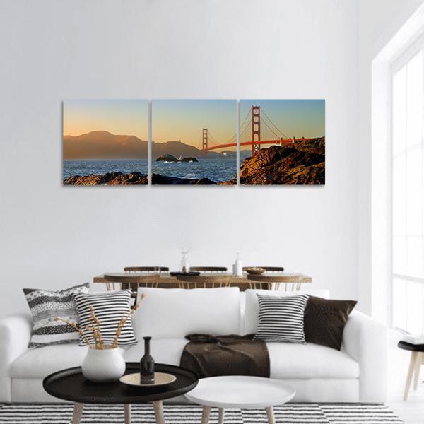 San Francisco Golden Gate Bridge Sunset Panoramic Canvas Wall Art in orange, yellow and blue, hung on a wall
