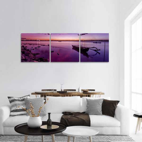 Lavender Beach Sunset with Outrigger Boat Panoramic Canvas Wall Art in orange, purple and pink, hung on a wall
