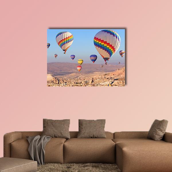 Cappadocia Hot Air Balloons Over Canyon Canvas Wall Art in beige, blue and multicolor, single panel hung on a wall
