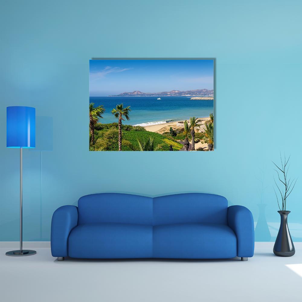 Tropical Beach with Palm Trees and Sailboat Canvas Wall Art in beige, green and blue, single panel hung on a wall