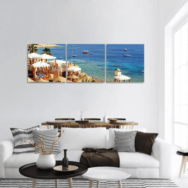 Beach Resort Over Turquoise Coral Reef Panoramic Canvas Wall Art in white, beige and blue, hung on a wall