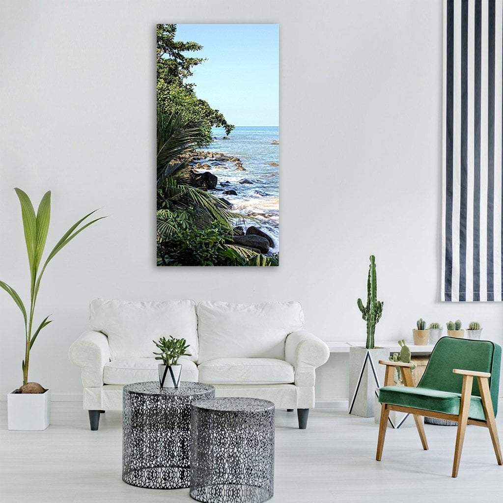 Tropical Rocky Shoreline with Palm Fronds Vertical Canvas Wall Art in green and blue, single vertical panel hung on a wall