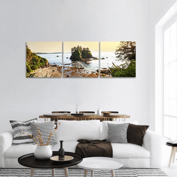 Golden Hour Coastal Beach with Tree-covered Islet Panoramic Canvas Wall Art in yellow, green and blue, hung on a wall