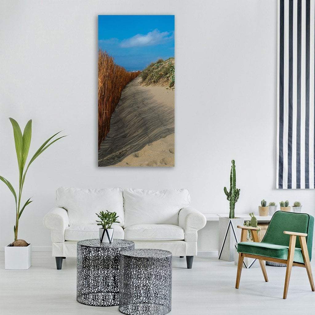 Sandy Dune Path with Reed Fence Vertical Canvas Wall Art in beige, brown and blue, single vertical panel hung on a wall