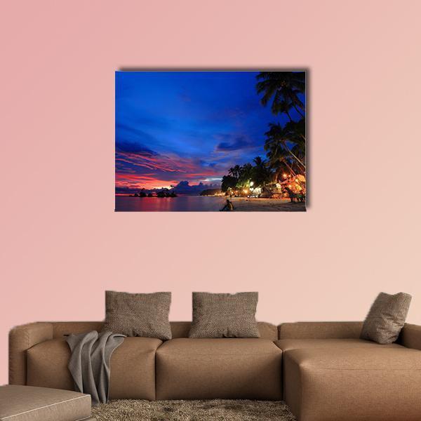 Tropical Beach Sunset with Palm Trees Canvas Wall Art in orange, blue and pink, single panel hung on a wall