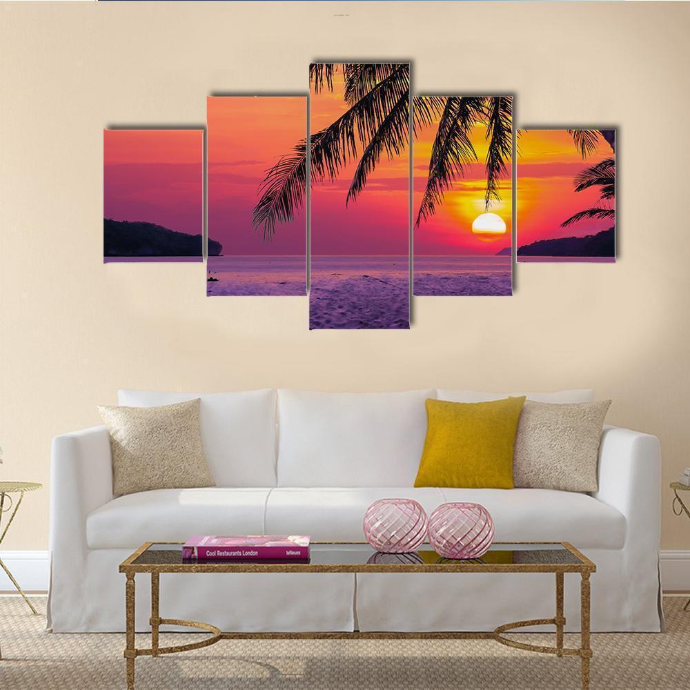 Coconut Tree at Sunset Beach Canvas Wall Art in orange, purple and pink, 5 panel Star layout hung on a wall