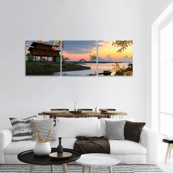Autumn Lakeside Village at Sunset Panoramic Canvas Wall Art in orange, yellow and blue, hung on a wall