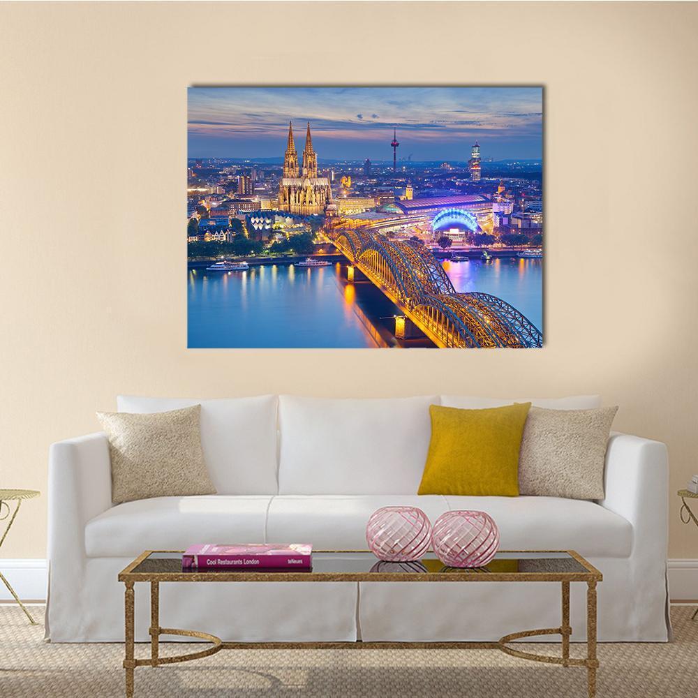 Cologne Cathedral and Hohenzollern Bridge Canvas Wall Art in orange, yellow and blue, single panel hung on a wall