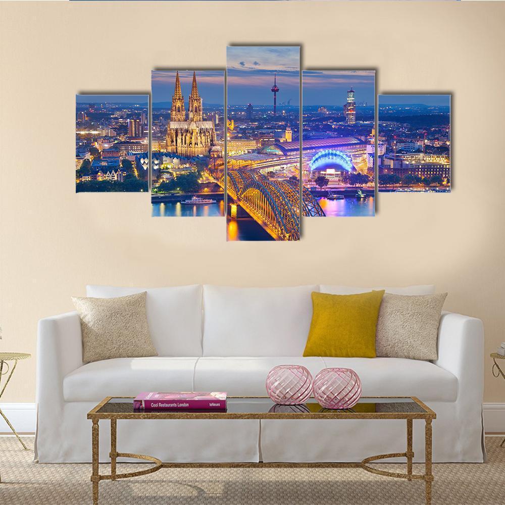 Cologne Cathedral and Hohenzollern Bridge at Dusk Canvas Wall Art in orange, yellow and blue, 5 panel Star layout hung on a wall