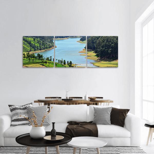 Winding Lake with Lush Green Hills Panoramic Canvas Wall Art in green and blue, hung on a wall