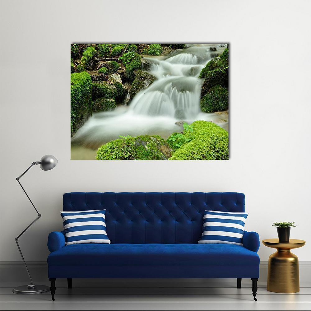 Forest Waterfall with Mossy Rocks Canvas Wall Art in white, gray and green, single panel hung on a wall