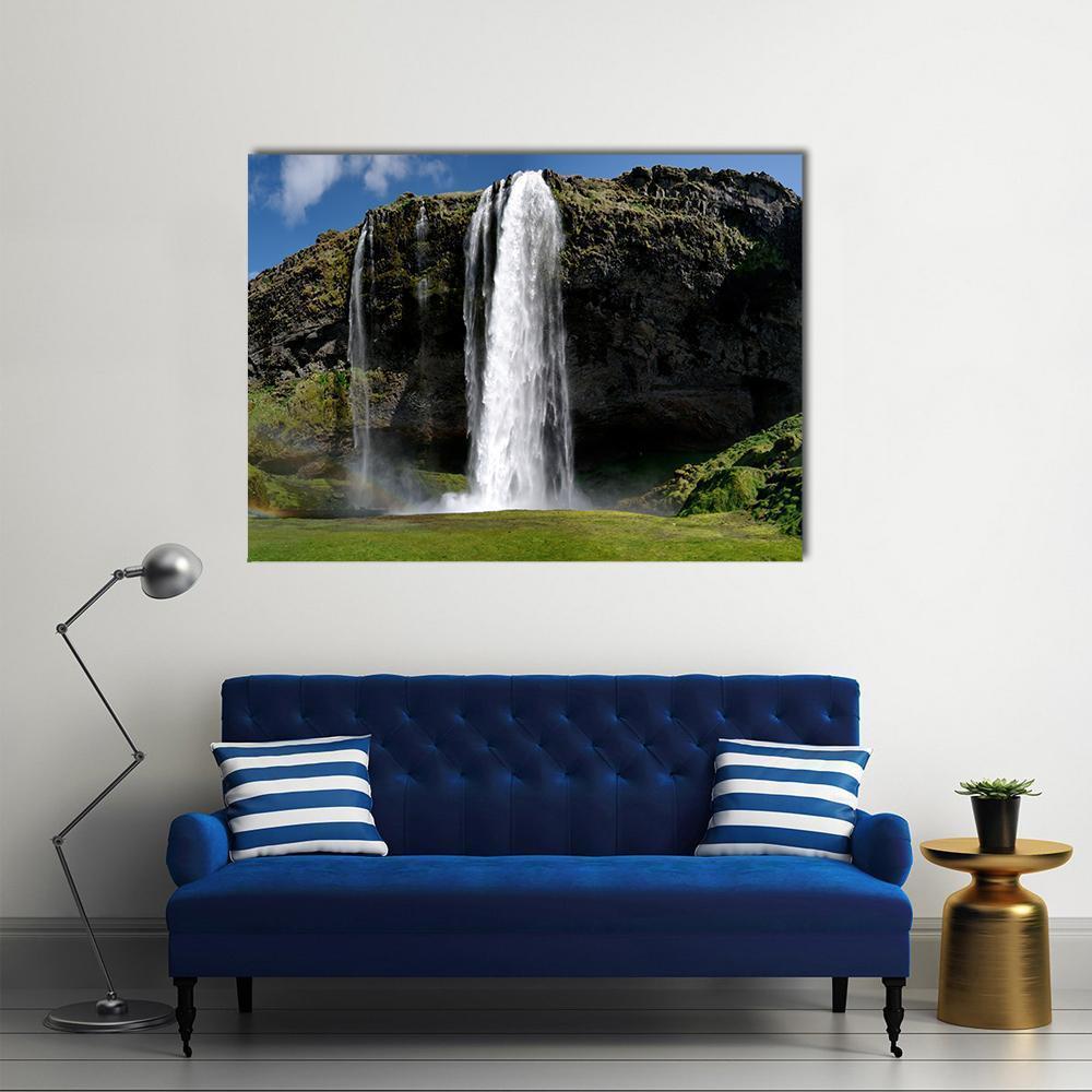 Waterfall Over Moss-covered Cliff Canvas Wall Art in gray, green and blue, single panel hung on a wall
