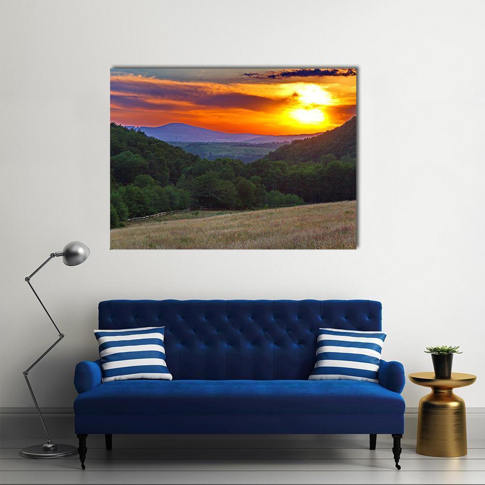 Sunset Over Forested Mountain Valley Canvas Wall Art in orange, yellow and green, single panel hung on a wall
