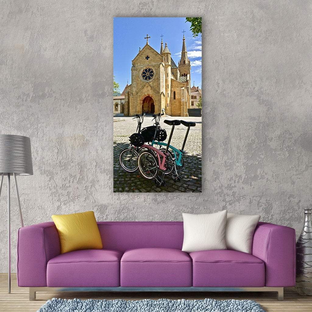 Two Bicycles in Front of Cathedral Vertical Canvas Wall Art in beige, brown and blue, single vertical panel hung on a wall