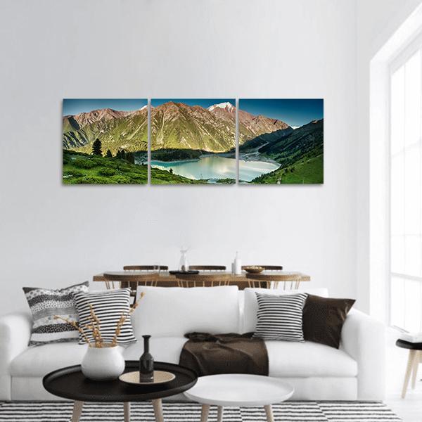 Big Almaty Lake Mountain Reflection Panoramic Canvas Wall Art in brown, green and blue, hung on a wall